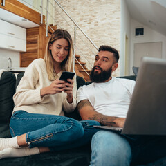 Wall Mural - Couple using a laptop and a smartphone at home