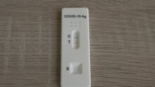 Tilting down slowly to a Covid 19 positive antigen test on a wooden table 23.98 fps