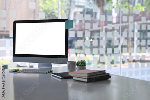 Obraz Dibond Modern office with computer, books, coffee cup and plant on white office desk.