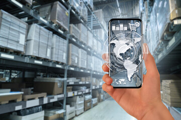 Poster - Hand with a phone on the background of a warehouse. Online trade and logistics concept
