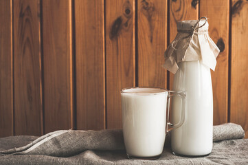 Fresh homemade milk on a brown wooden background.  A eco bottle of milk and glass of milk on a tablecloth