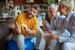 © luckybusiness - Elderly business women enjoy watching a smartphone content their young male colleague showing to them while they take a break at workplace. Business, office, job