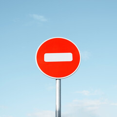 Round road sign No Entry, on a pole against a clear blue sky.