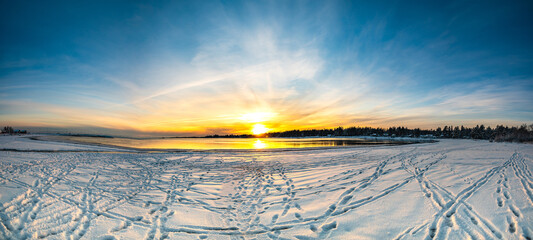 The panoroma of yellow horizon and sunset in snow-covered sea beach