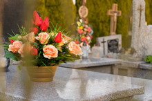 A Tomb Decorated With Candles And Flowers With Cementary In The Background.