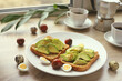 Toast with sliced avocado quail eggs cherry tomatoes and coffee. Healthy breakfast.