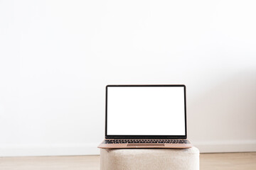 Black laptop wiith white screen on wooden table in home scandi interior. Stylish minimalistick workplace, copy space