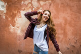 Fototapeta Tematy - Happy teenage girl enjoying and dancing with a red wall background with copy space