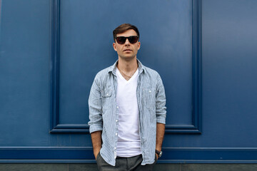 Handsome brunette man in sunglasses on blue background