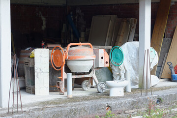 orange and green concrete mixer under a house in construction