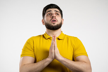 Young caucasian man praying over white background. Guy begging someone satisfy his desires, help with.