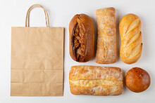 Baking Background With Eco Disposable Paper Bag From A Supermarket Recyclable And Whole Fresh Baked Loaves Of Bread Top View On Gray Background With Mockup