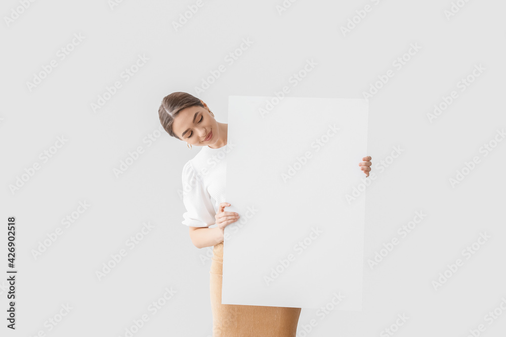 Beautiful young woman with blank poster on light background Stock Photo ...