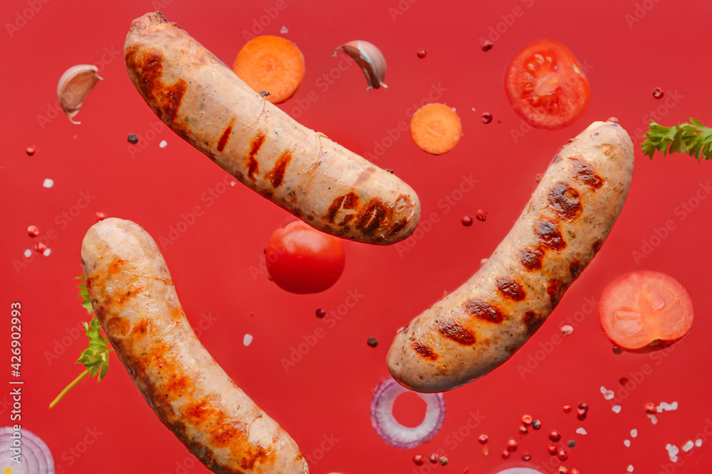 Delicious grilled sausages and vegetables on color background