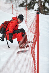 Male snowboarder in a red suit rides on the snowy hill with snowboard, Skiing and snowboarding concept