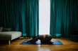 © shevtsovy - Young woman practicing yoga at home. meditation practice. Relaxation and meditation in living room. Beautiful fitness female wearing yoga pants gymnastics morning routine. Posture practicing