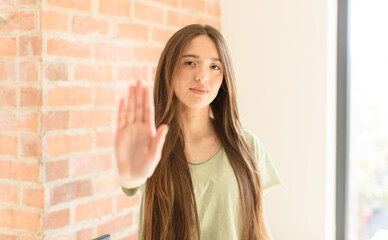 pretty woman looking serious, stern, displeased and angry showing open palm making stop gesture