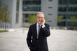 © Minerva Studio - Senior businessman using his cellphone outdoor while walking in a city