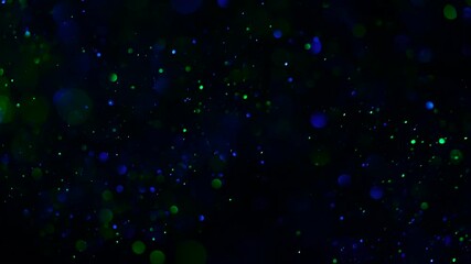 Poster - Beautiful sparkle dust on a black background in blue-green light. Slow motion.