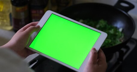 Wall Mural - over shoulder view of woman holding green screen tablet when cooking in the kitchen