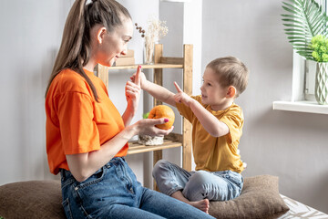 a happy mother in a playful way is teaching her little son to count using fruits. concept of family,