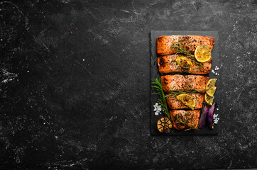 Salmon. Pieces of grilled fish on a black stone background. Recipe. Seafood. Free space for text.