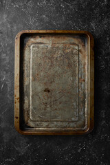 Old metal kitchen tray on a black stone background. Retro tableware. Free space for text.