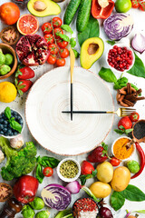 The concept of dietary nutrition: fresh vegetables and fruits. Cutlery and a plate in the form of a clock. Top view. Free space for your text.