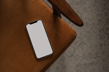 Blank screen mobile phone on vintage chair. Flat lay, top view minimalist blog, website, app template. Copy space smartphone mockup.