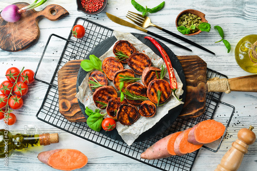 Obraz Dibond Fried sweet potatoes with rosemary, paprika and chili peppers on a black stone plate. Top view. Free space for your text.