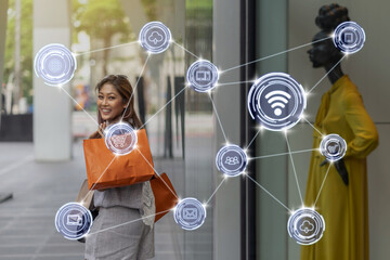 Wireless communication connecting of smart city Internet of Things Technology over Asian woman walking and looking through the glassess into the clothes on model display mockup in store shop