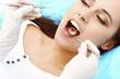 © rogerphoto - Young female patient visiting dentist office.Beautiful woman with healthy straight white teeth sitting at dental chair with open mouth during oral checkup while doctor working at teeth