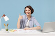 © ViDi Studio - Young operator employee business woman in shirt set microphone headset for helpline assistance sit work at office desk with pc laptop show thumb up gesture isolated on pastel blue background studio.