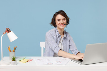 Young operator fun employee business woman in shirt set microphone headset helpline assistance sit work at office desk with pc laptop surfing internet online isolated on pastel blue background studio.