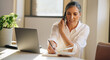 © Jacob Lund - Businesswoman talking on cell phone and taking notes in office