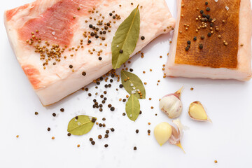 raw lard two pieces and salt, spices and bay leaf on white background, pork fat