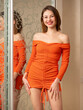 Beautiful, young woman with a good figure posing in an orange dress at home 