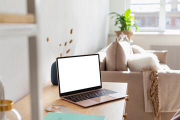 Pink laptop wiith white screen on wooden table in home scandi interior. Stylish minimalistick workplace, copy space