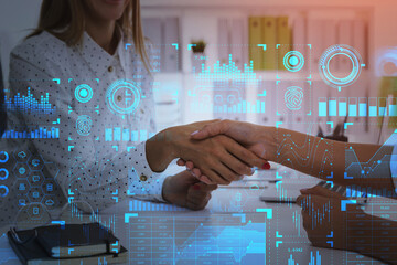 Two attractive businesswomen shake hands at office workplace