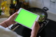 © Robert - over shoulder view of woman holding green screen tablet when cooking in the kitchen