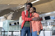 © DimaBerlin - Happy black couple in love wait for flight in airport. Young romantic african man and woman before departure for vacation or honeymoon trip hug and smile. Casual afro guy and girl travel by plane