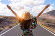 woman on a deserted road in front of the sea raising her arms for the freedom she feels - selective focus - summer concept