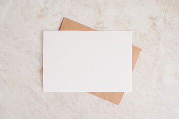 blank card mock up. layout of sheet of paper on craft envelope and marble texture. horizontal canvas