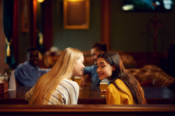 Wall Mural - Four friends drinks alcohol and talking in bar