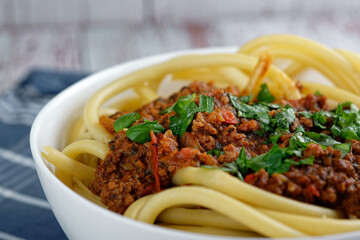 Wall Mural - Close up of Italian pasta with bolognese, in a bowl. On rough gray wooden boards.