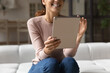 Modern tech at home. Close up of smiling young lady hold electronic tablet pc use entertainment app enjoy video game. Happy female sit on couch touch modern pad screen do shopping on ecommerce website