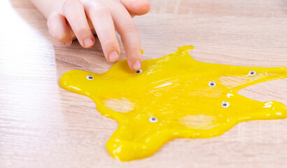 Yellow slime spreads across the table. Lots of small eyes are added to the yellow slime. Play Slime Toy