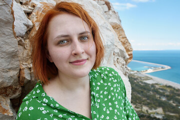 Wall Mural - Portrait of young redhead Caucasian woman near cliff above sea in Antalya in spring.