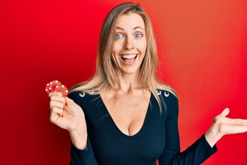 Poster - Beautiful caucasian woman playing poker holding casino chips celebrating achievement with happy smile and winner expression with raised hand