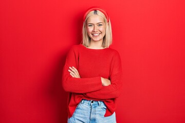 Beautiful blonde woman wearing casual red sweater happy face smiling with crossed arms looking at the camera. positive person.